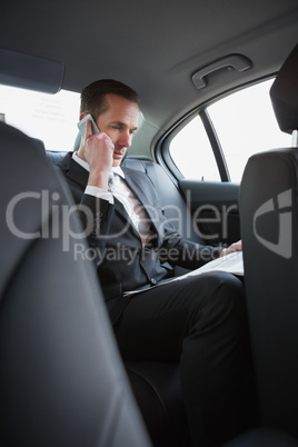 Businessman on the phone reading the newspaper Businessman on the phone reading the newspaper