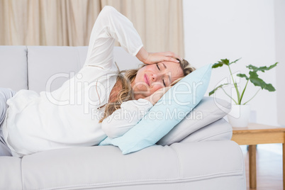 Grimacing blonde lying on couch getting headache