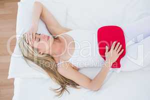Woman using hot water bottle for her stomach pain