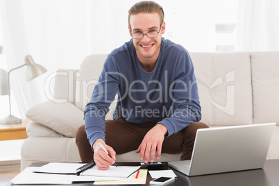 Smiling man using calculator counting his bills