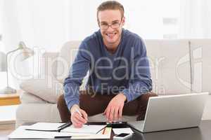 Smiling man using calculator counting his bills