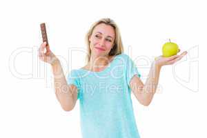 Smiling blonde holding bar of chocolate and apple