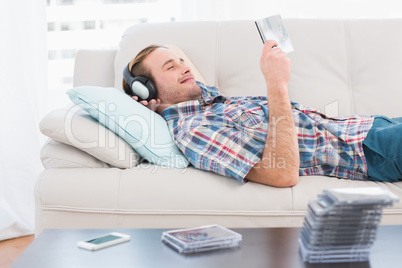 Relaxed man listening music lying on sofa