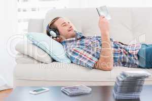 Relaxed man listening music lying on sofa