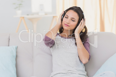 Pretty brunette listening to music on the couch