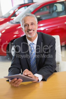 Smiling businessman using tablet at his desk