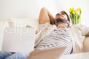 Hipster man using laptop lying on couch