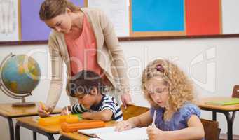 Pretty teacher helping pupil in classroom