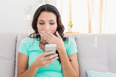 Shocked brunette texting on the phone