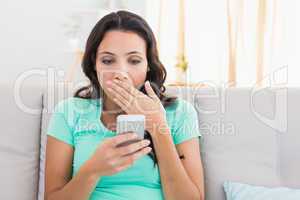 Shocked brunette texting on the phone