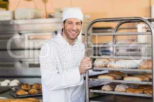 Smiling baker pushing tray of bread