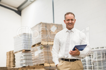 Manager standing with hand in the pocket holding tablet pc
