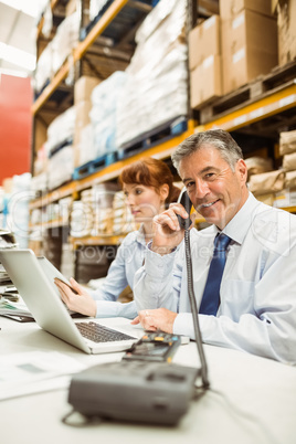 Manager working on laptop and talking on phone at desk