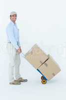 Confident delivery man pushing trolley of cardboard boxes