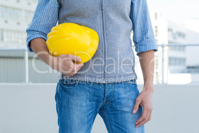 Male architect holding yellow hard hat