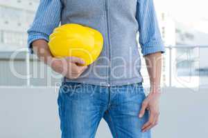Male architect holding yellow hard hat