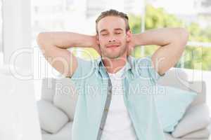 Cheerful businessman resting with hands behind head
