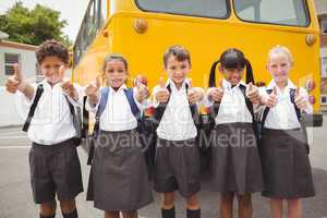 Cute schoolchildren smiling at camera by the school bus