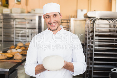 Smiling baker holding raw dough