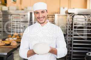 Smiling baker holding raw dough