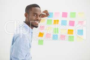 Smiling businessman writing on sticky notes