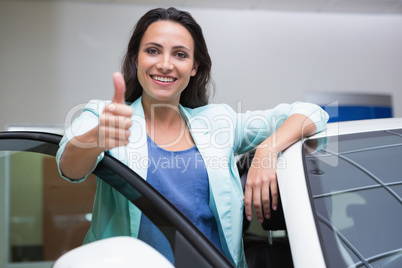 Smiling customer leaning on car while giving thumbs up