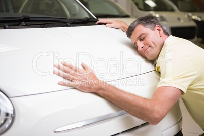 Smiling man hugging a white car