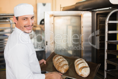 Happy baker holding tray of fresh bread