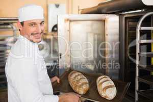 Happy baker holding tray of fresh bread