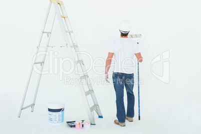 Man with paint roller standing by ladder