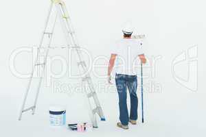 Man with paint roller standing by ladder