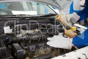 Mechanic pouring oil into car