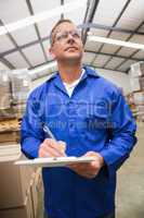Warehouse worker checking his list on clipboard