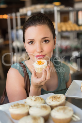 Pretty brunette smelling a cupcake