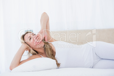 Blonde woman lying in bed yawning