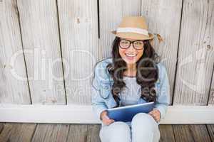 Pretty hipster sitting on ground with tablet