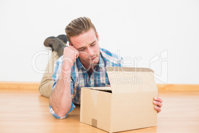 Disappointed man lying on the floor opening gift