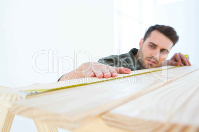 Worker measuring wooden plank