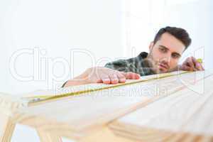 Worker measuring wooden plank