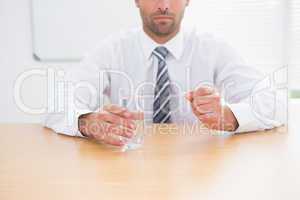 Serious businessman holding glass of water and tablet