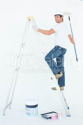 Happy man on ladder painting with roller