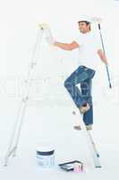 Happy man on ladder painting with roller