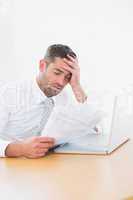 Confused businessman looking at his paper