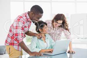 Smiling coworkers interacting and using laptop