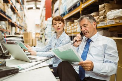 Manager working on laptop and talking on phone at desk