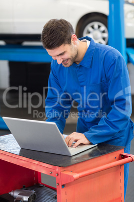 Smiling mechanic using his laptop