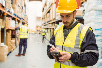 Focused worker wearing yellow vest using handheld