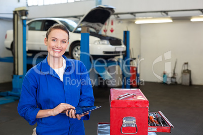 Mechanic smiling at the camera using tablet