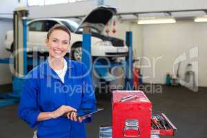 Mechanic smiling at the camera using tablet