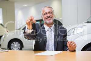 Salesman sitting while offering car keys